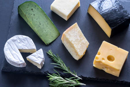 Various types of cheese on the black stony boardの写真素材