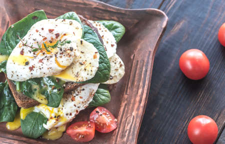 Sandwich with poached eggs, mozzarella, spinach and cherry tomatoesの写真素材