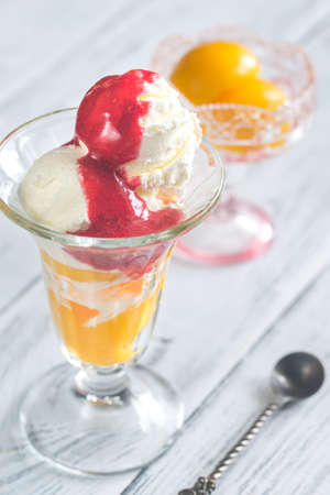 A bowl of Peach Melba - vanilla ice cream with peaches and raspberry sauceの写真素材
