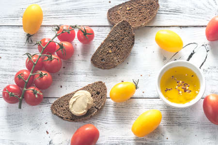 Fresh tomatoes with slices of dark-rye bread on the wooden background