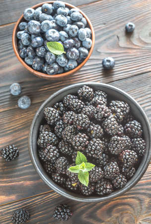 Bowls of blackberries and blueberries on the wooden tableの写真素材