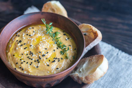 Bowl of pumpkin hummus with slices of toasted breadの写真素材