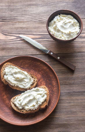 Toasts with cream cheese on a wooden tableの写真素材