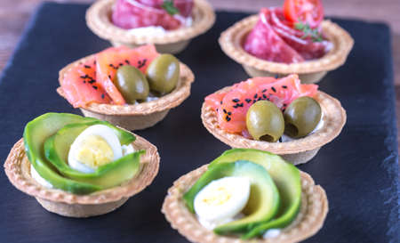 Tartlets with different fillings on the stone boardの写真素材