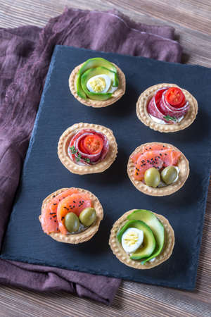 Tartlets with different fillings on the stone board
