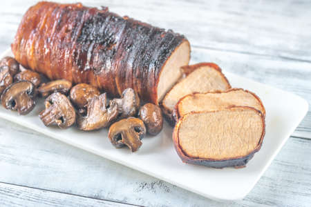 Pork loin wrapped in bacon with roasted mushroomsの写真素材