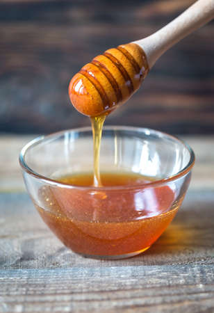 Bowl of honey on the dark wooden backgroundの写真素材