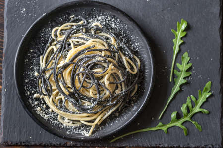 Mix of white and black pasta with cheese in the bowlの写真素材