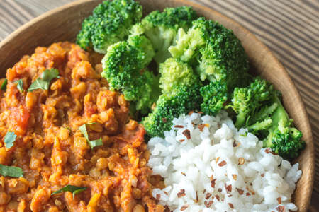 Bowl of red lentil curry with white rice and broccoliの写真素材