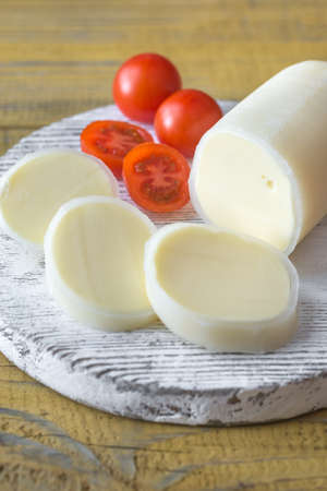 Sliced Formaggio with cherry tomatoes on the wooden board