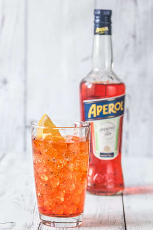 SUMY, UKRAINE - AUGUST 29, 2018: Glass of Aperol Spritz cocktail with bottle of Aperol on the white wooden background. Aperol is famous Italian aperitif.のeditorial素材
