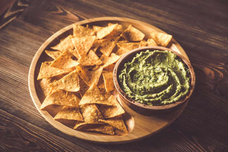 Guacamole with tortilla chips on the wooden tray