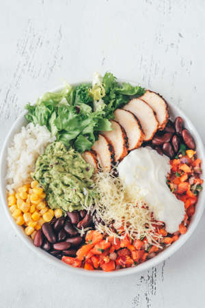 Burrito bowl with chicken, salsa, corn, rice, kidney beans and guacamole