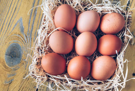 Basket of raw chicken eggs on the wooden backgroundの写真素材