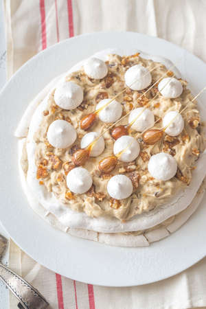 Pavlova cake with caramel and almonds on the wooden