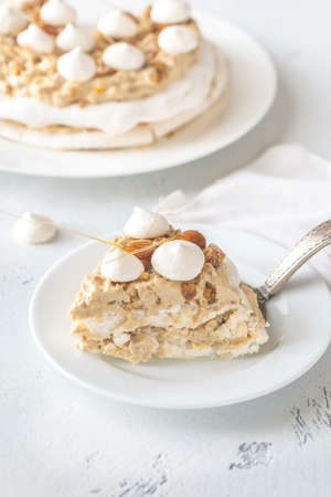Pavlova cake with caramel and almonds on the wooden