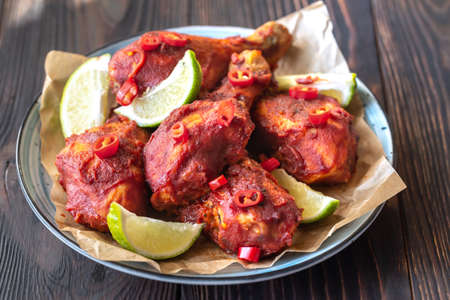 Chicken drumsticks in barbecue sauce garnished with lime wedges