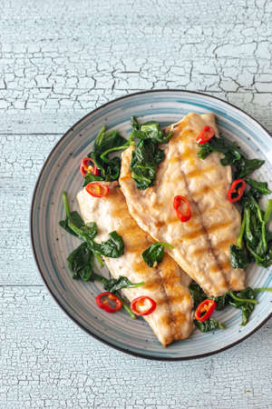 Grilled sea bream fish fillet with spinach and chili pepper