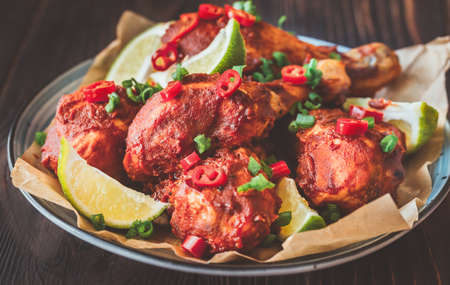 Chicken drumsticks in barbecue sauce garnished with lime wedgesの写真素材