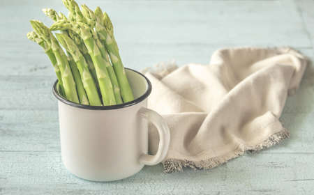 Bunch of fresh asparagus in the white mugの写真素材