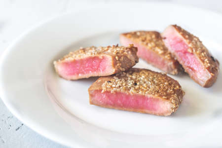 Fried tuna in sesame seeds on the white plate: cross sectionの写真素材