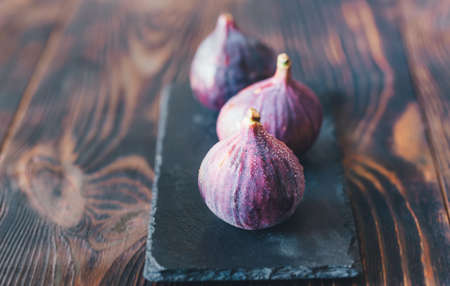 Three fresh figs on the black stone boardの写真素材
