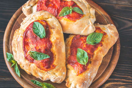 Homemade calzone stuffed with pancetta and mushrooms on the wooden boardの写真素材