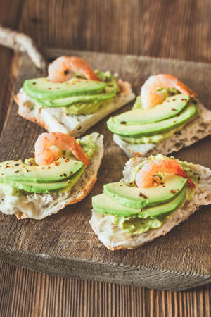 Sandwiches with guacamole, sliced avocado and shrimps on the wooden boardの写真素材