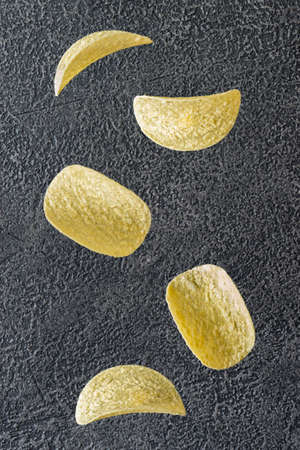 Falling potato chips on the dark backgroundの写真素材