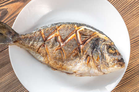 Fried sea bream on the plate: top view