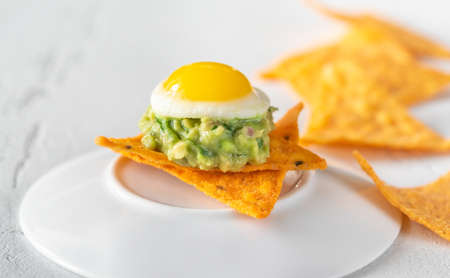Appetizer with tortilla chips, guacamole and fried quail eggの写真素材