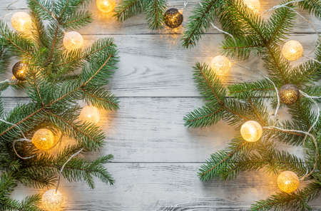 Christmas tree branches with lights on the wooden backgroundの写真素材
