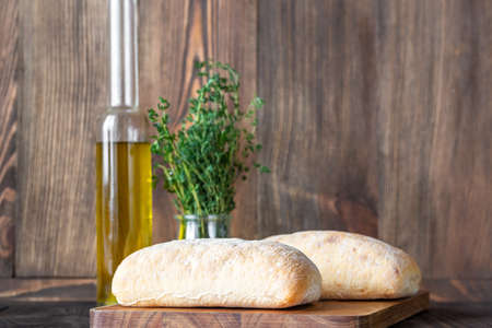 Ciabatta - Italian white bread with a glass bottle of olive oil on wooden backgroundの写真素材