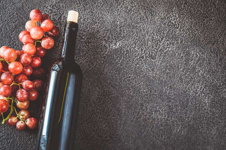 Bottle of red wine with bunch of grapes flat lay