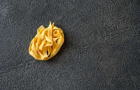 Raw pappardelle - flat Italian pasta noodles on wooden backgroundの写真素材
