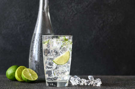 Glass of sparkling water with ice cubes and slice of lime