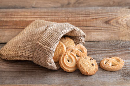 Butter cookies in burlap bag on wooden tableの写真素材