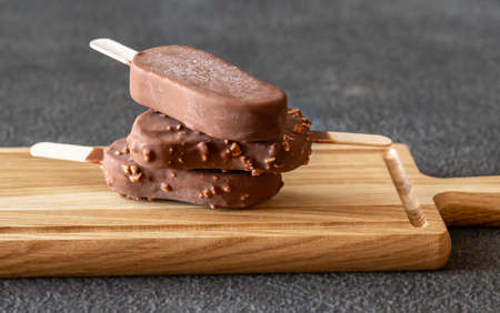 Chocolate-covered vanilla ice cream bars on the wooden board