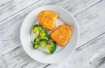 Portion of battered fish with steamed broccoliの写真素材