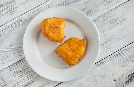 Slices of battered fish on a white plate