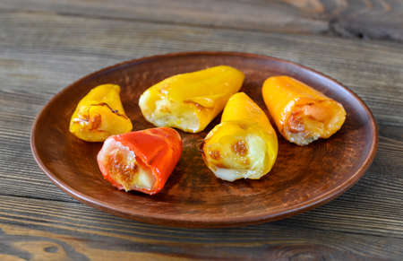 Stuffed mini sweet peppers with mozzarella on a white plateの写真素材