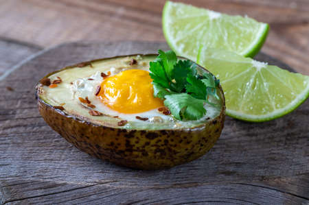 Baked egg in avocado on the wooden board: top view