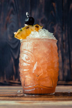 Glass of Jungle Bird cocktail garnished with pineapple wedge