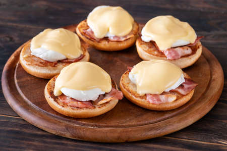 Eggs Benedict with bacon on wooden boardの写真素材