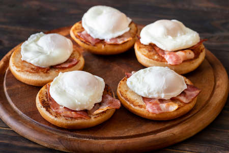Eggs Benedict with bacon on wooden boardの写真素材