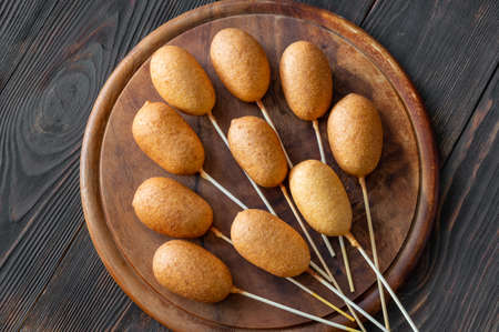 Bunch of mini corn dogs on wooden board