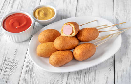 Corn dogs with dip sauces on white serving plateの写真素材