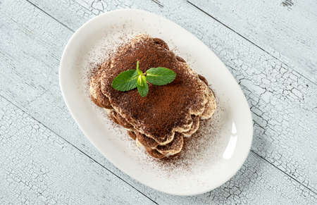 Portion of tiramisu on white serving plateの写真素材