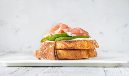 Toast with slices of avocado, prosciutto and cream cheeseの写真素材