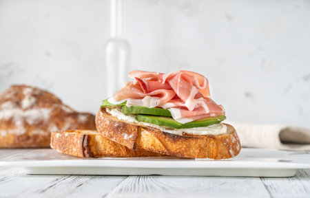 Toast with slices of avocado, prosciutto and cream cheeseの写真素材